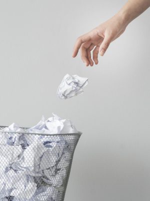 Woman hand throwing crumpled paper in basket